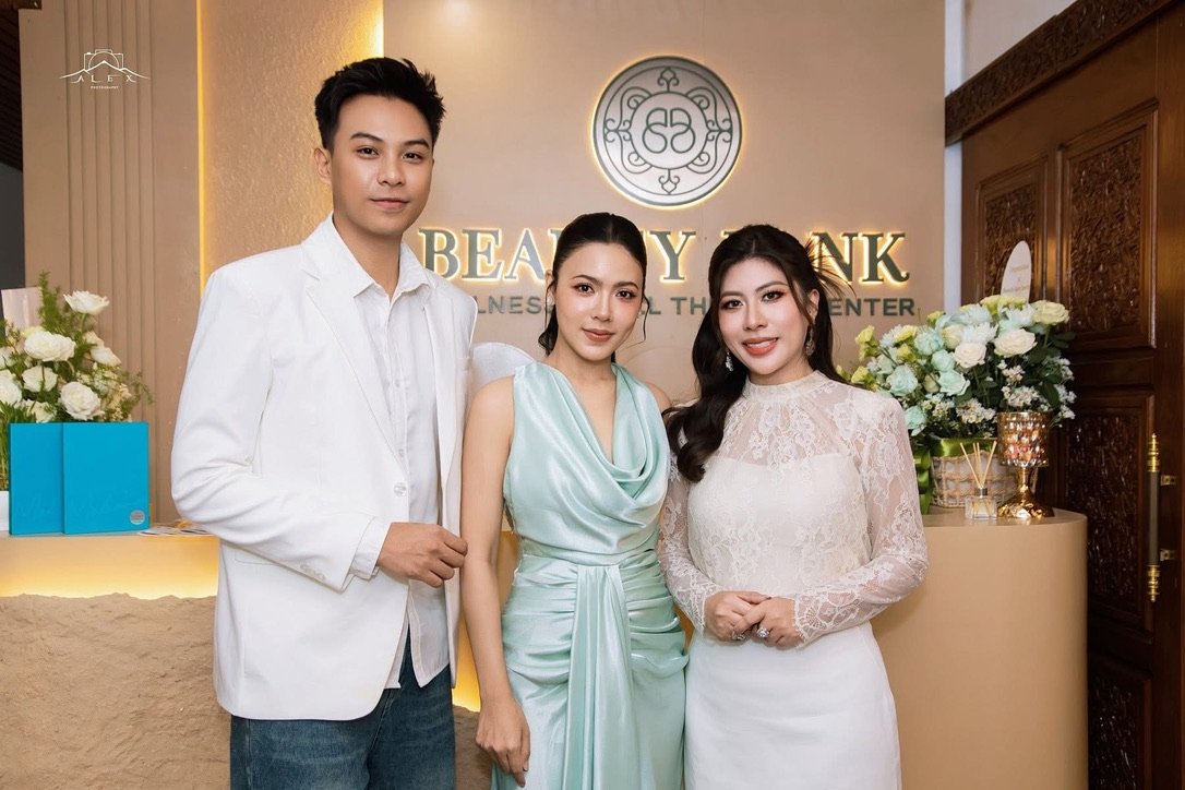 The Beauty Bank founding principals at the reception counter on opening day, framed by the illuminated clinic sign and a floral welcome.