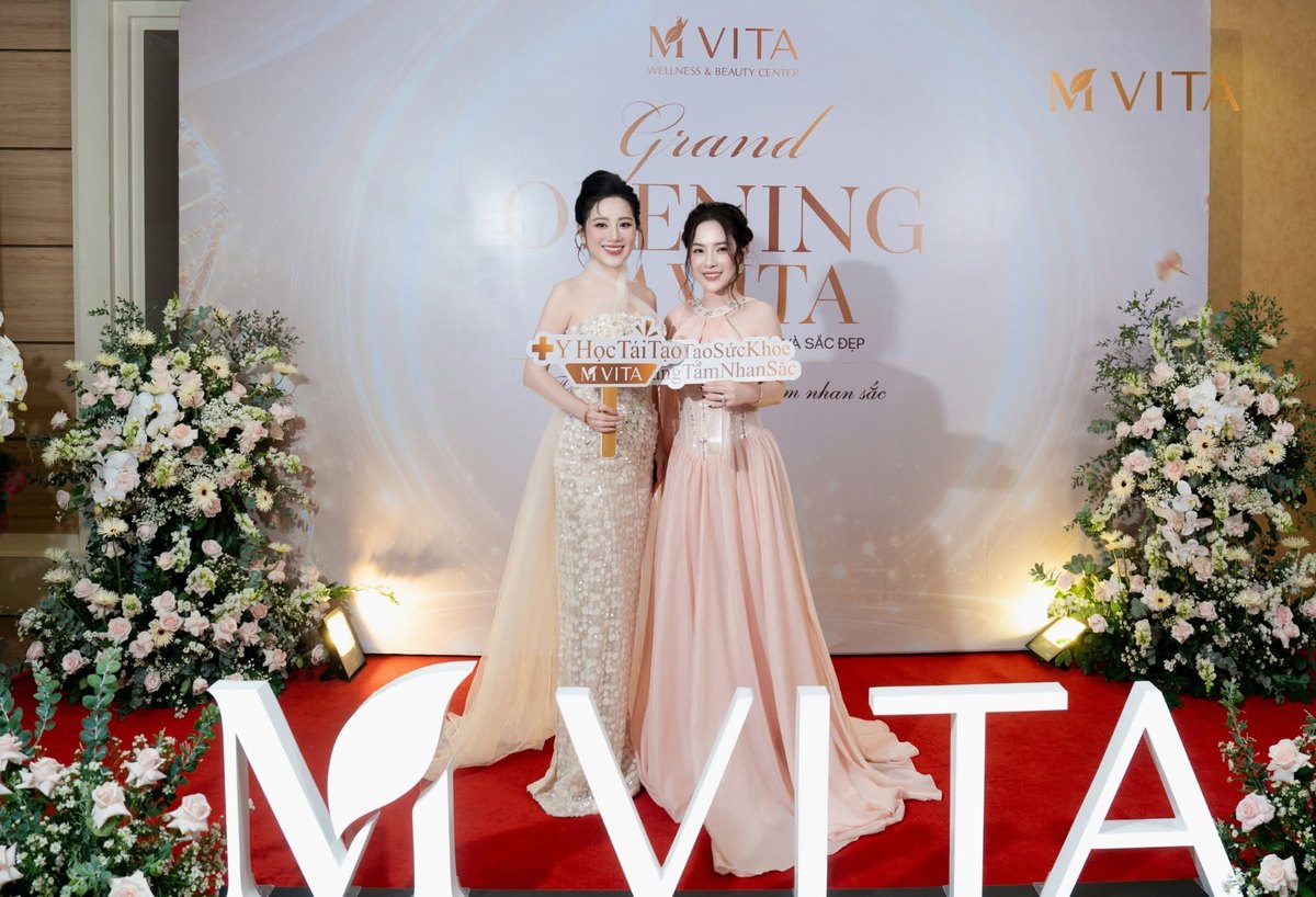 M VITA hosts on the red carpet in front of the M VITA installation and floral arrangements at the ceremony entrance.