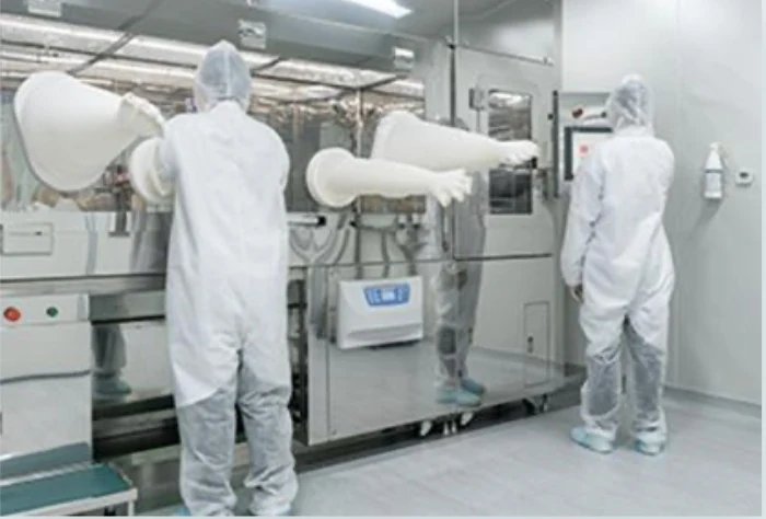 Technicians in full cleanroom gowns working at isolators in a Taiwanese laboratory